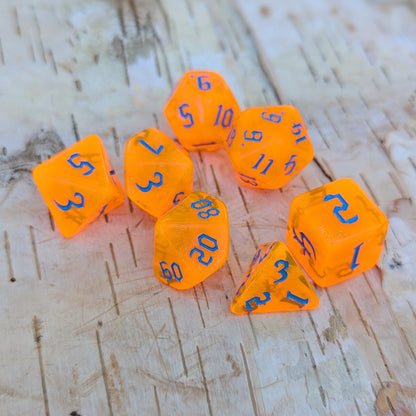 Pumpkin Orange Will O Wisp TTRPG Dice Set with blue font for Dungeons and Dragons on a wooden surface.