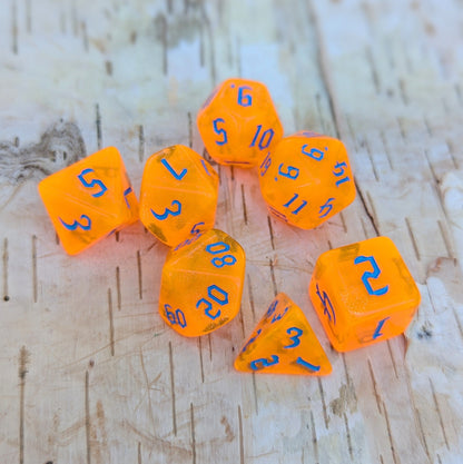 Pumpkin Orange Will O Wisp Dice Set with blue font, 7 polyhedral pieces for TTRPG, including D20, D12, D10, D%, D8, D6, D4.