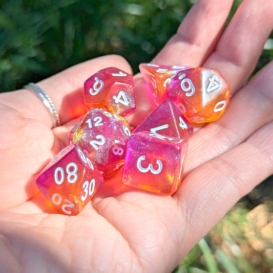 Hand holding a Purple and Orange Will O Wisp Dice Set with shimmering glitter for tabletop RPGs like Dungeons and Dragons.