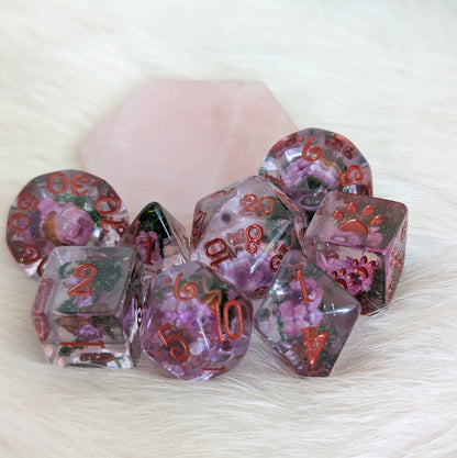 Purple flowers and moss dice set with coppery red font, featuring real dried flowers, glitter, and paw counters for tabletop games.