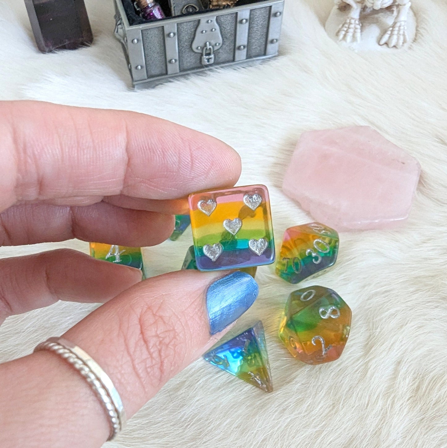 "Hand holding translucent rainbow heart dice set for Dungeons and Dragons"