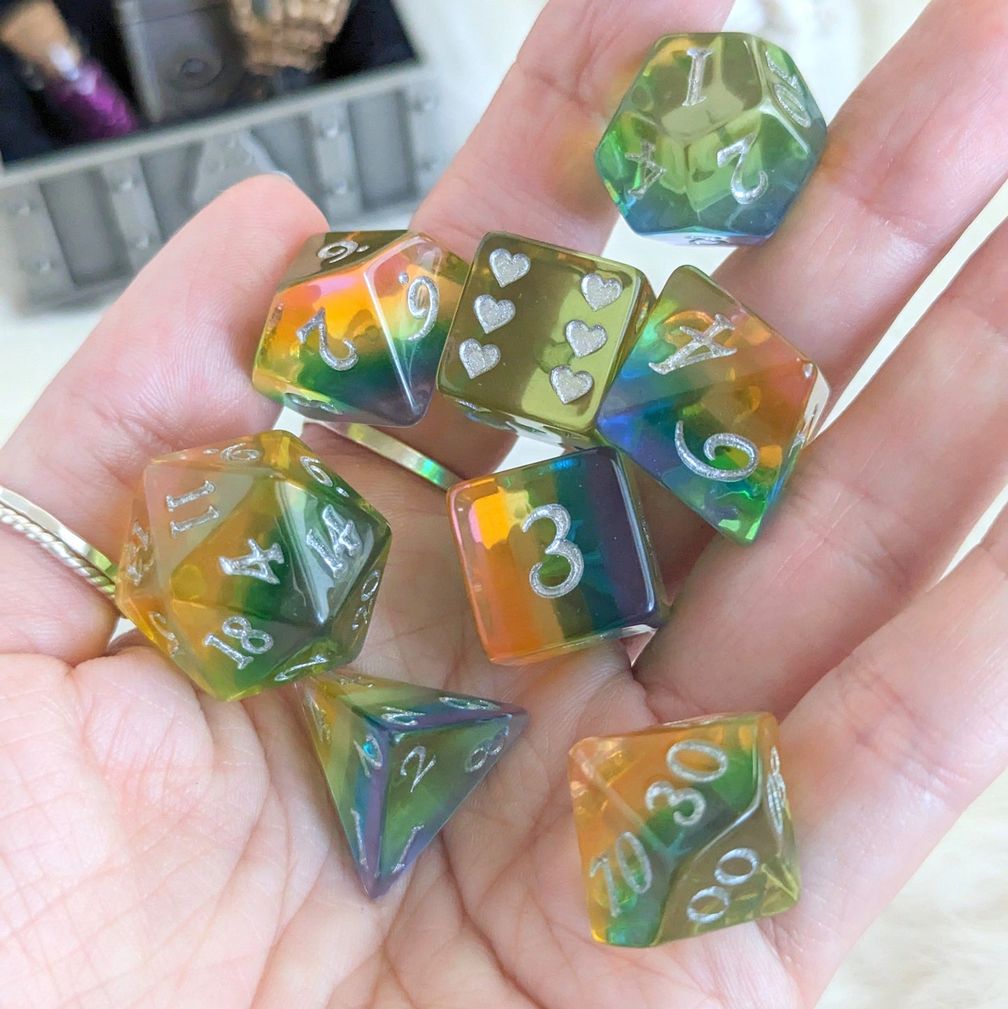 Hand holding translucent rainbow heart polyhedral dice set for tabletop games