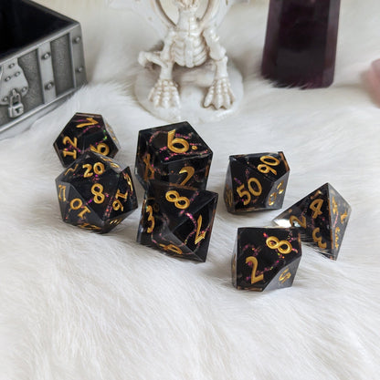 Black and red lightning DnD dice set with gold numbers, featuring a cracked design with glittering resin details, on a white surface.