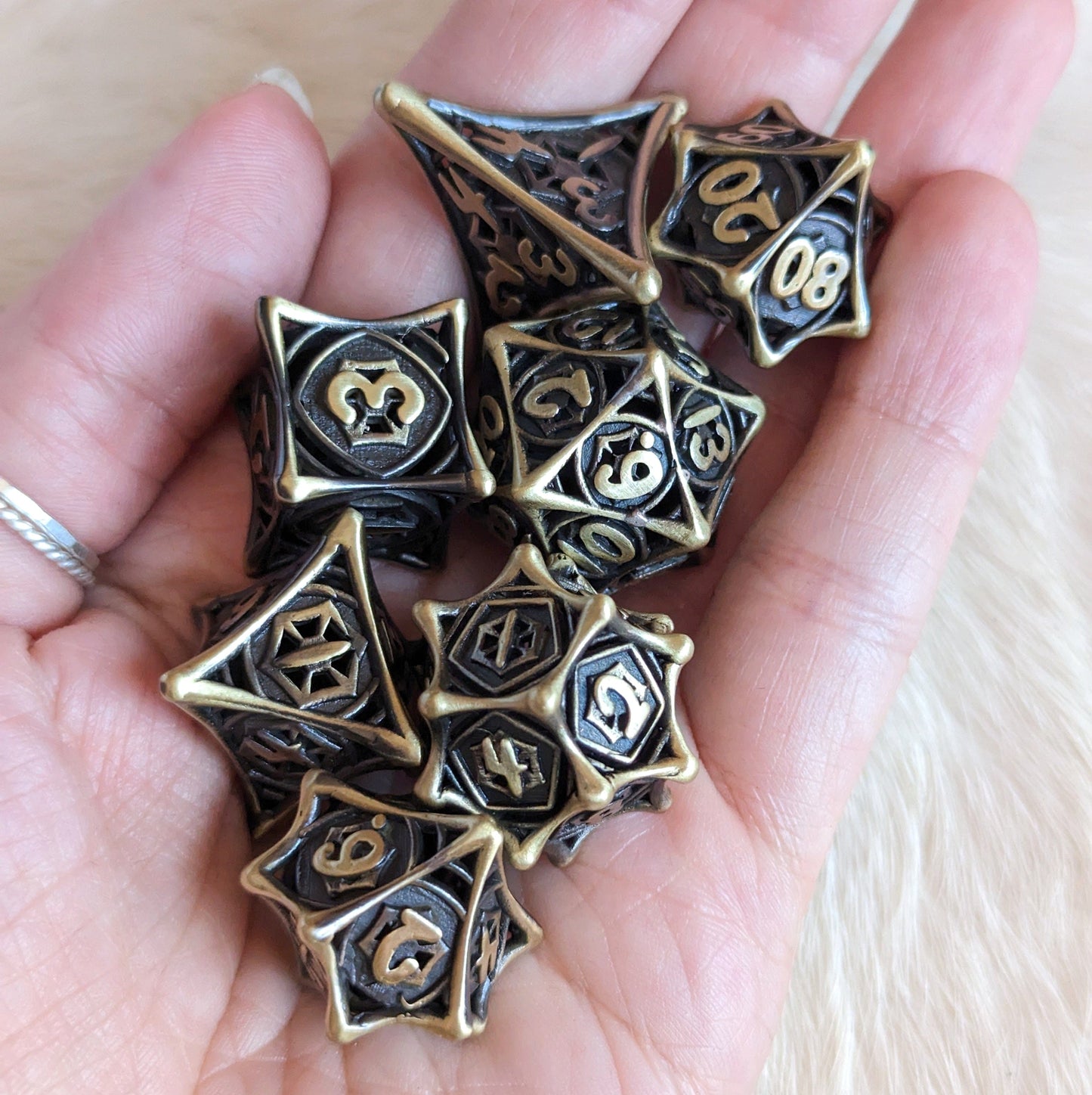 Hand holding a Spider Web Hollow Metal Dice Set, featuring intricate Celtic knot design, perfect for DnD and tabletop RPGs.