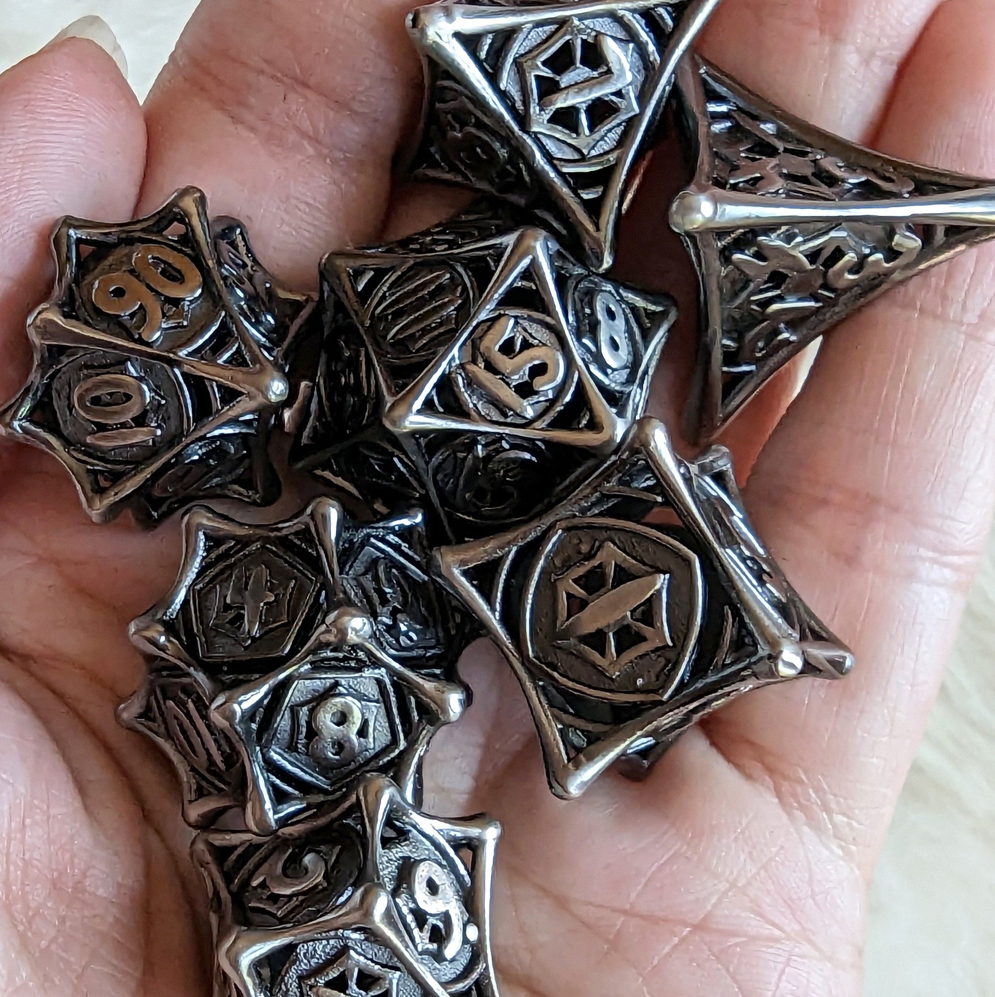 Hand holding Spider Web Hollow Metal Dice Set for tabletop RPGs