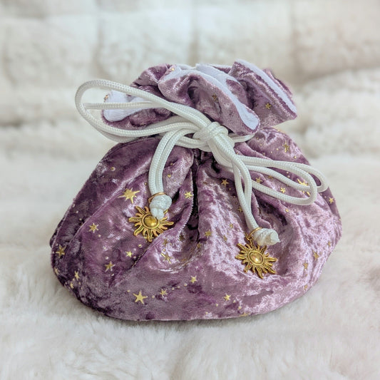 Mauve velvet dice bag with gold stars and solar charms, featuring multiple pockets and strong cord drawstrings on a soft fabric.