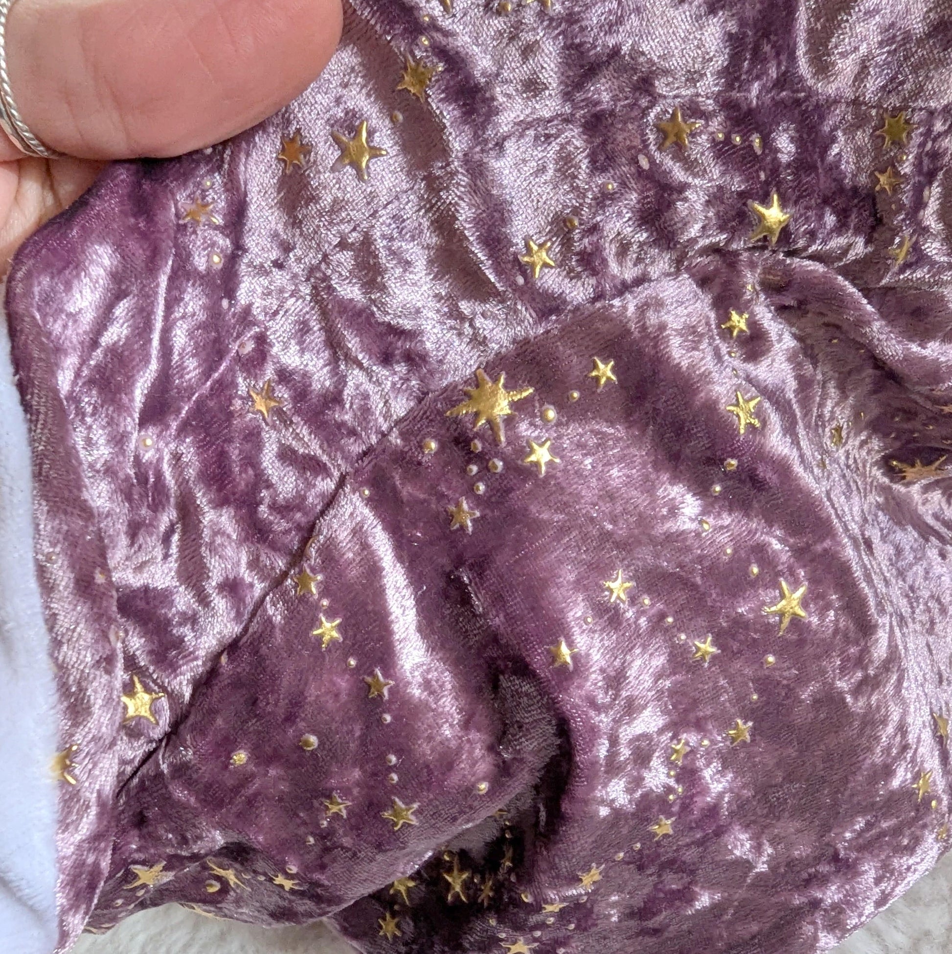 Mauve velvet fabric with gold star pattern, used for multi-pocket dice bag, soft texture, viewed close-up.