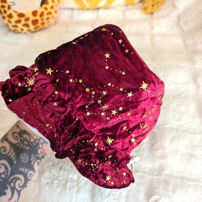 Luxurious red dice bag with golden stars, held in hand. Rich velvet fabric with multiple pockets and elegant details for tabletop gaming.