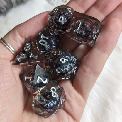 Hand holding Technicolor Moving Eye Liquid Core Dice Set with vibrant swirling colors and mesmerizing eyes in each die.