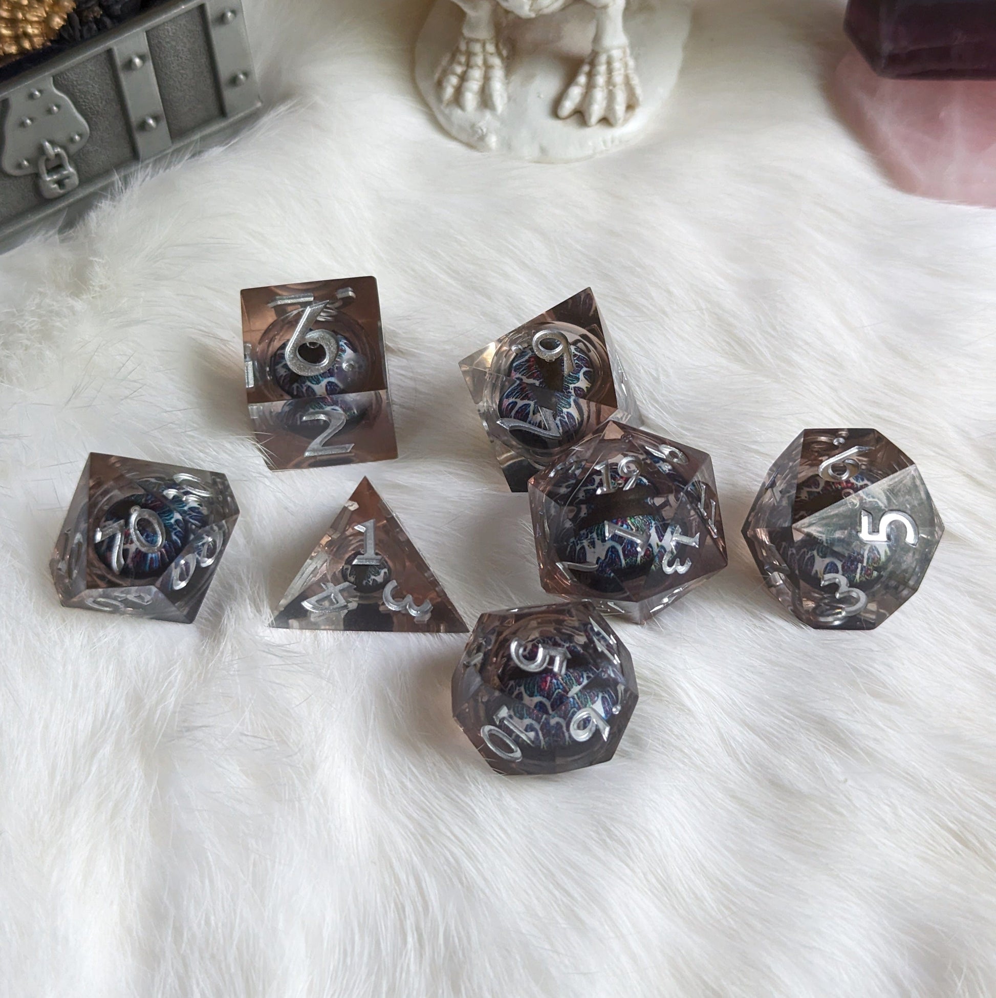 Technicolor Moving Eye Liquid Core Dice Set with swirling colors on fluffy white surface.