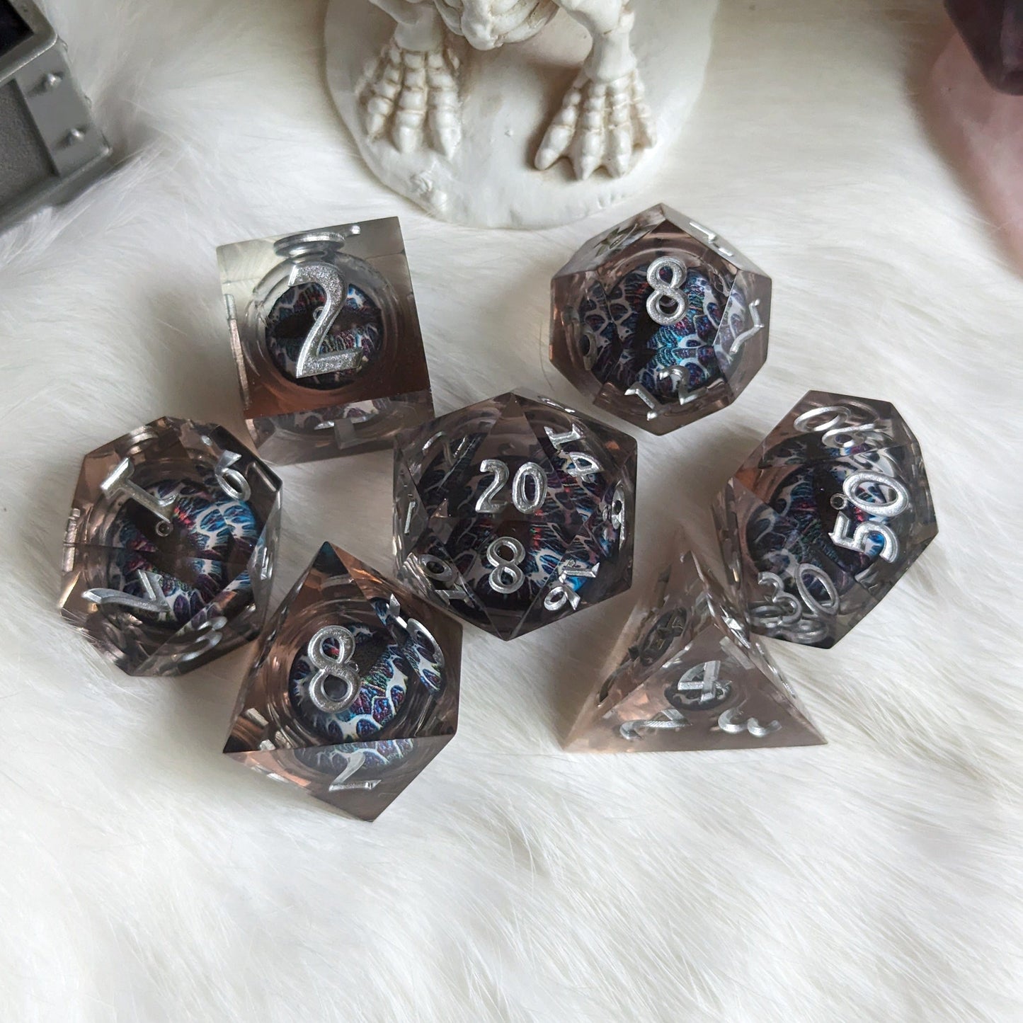 Technicolor Moving Eye Liquid Core Dice Set with swirling colors on a white furry surface.