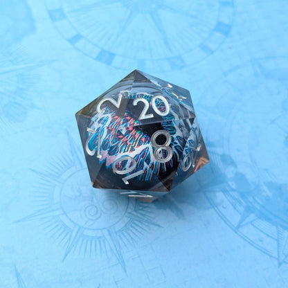 Clear resin D20 dice with a vibrant eye design in white, blue, black, and pink, set against a blue background.