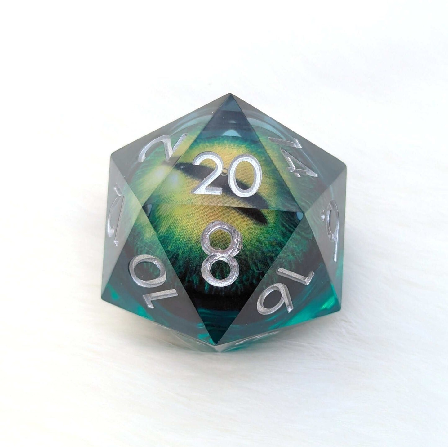 Large green D20 die with a moving eye at the center, crafted from green-tinted resin, featuring silver numbers.