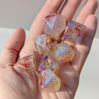 "Adoration 7 Piece Sharp Edge Dice Set with daisies and rose petals in purple blue shimmer for tabletop games like D&D and Magic."