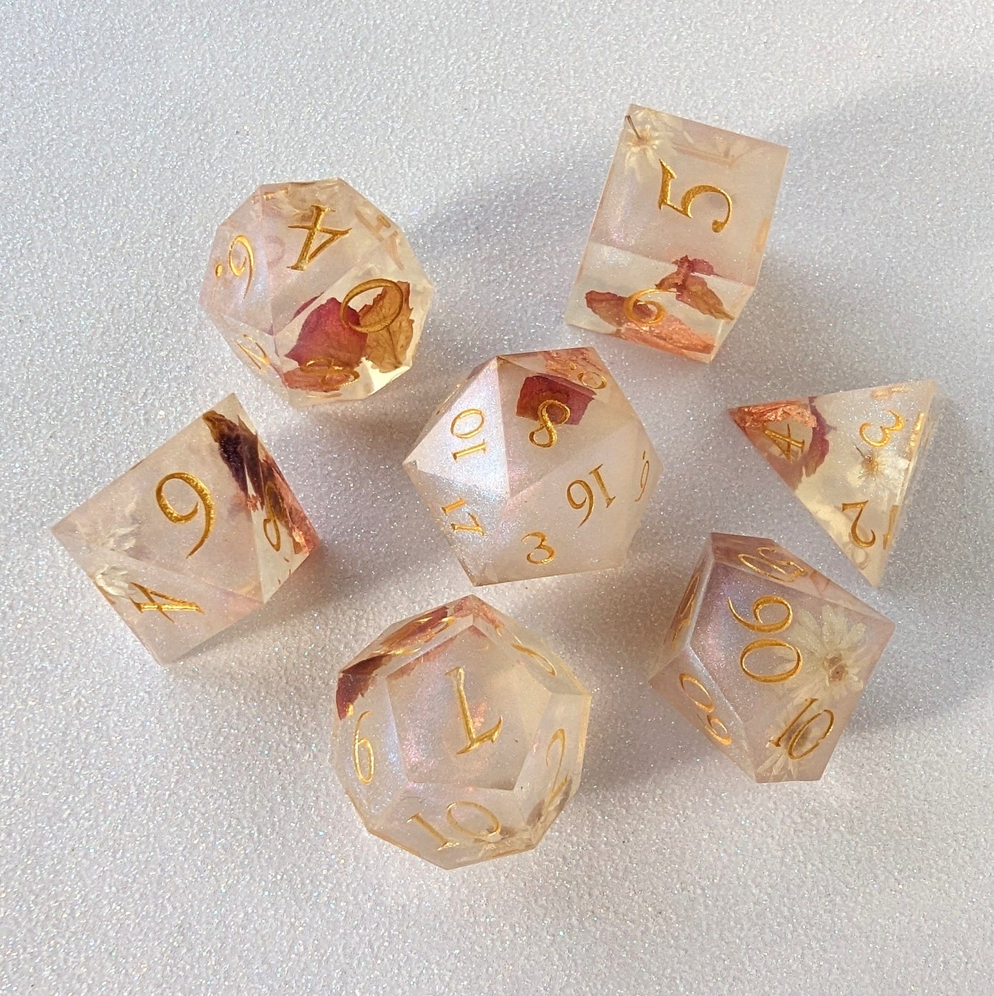 Sharp edge resin dice set with embedded rose petals and gold numbers, perfect for Dungeons and Dragons and tabletop games.