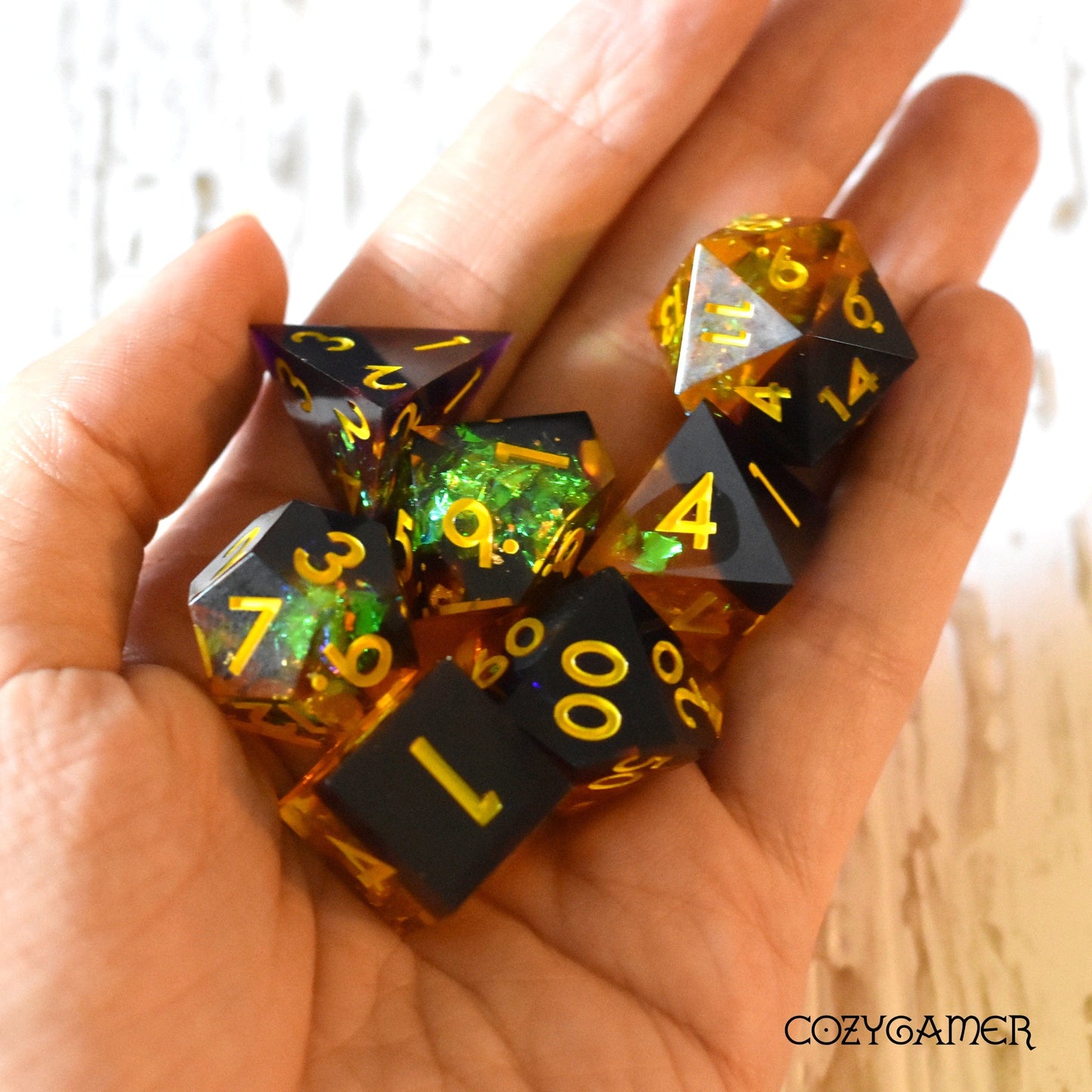 Hand holding Autumn Magic Sharp Edge Resin Dice Set, featuring a black and yellow glitter design, 7-piece DND polyhedral dice set.