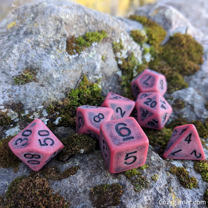 Matte red Blood DnD dice set on a mossy rock, 7-piece polyhedral resin dice for tabletop role-playing games like Dungeons and Dragons.