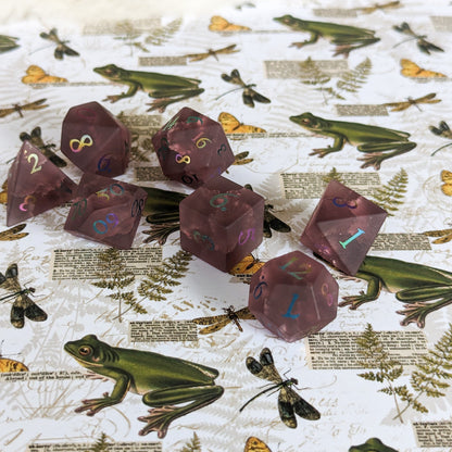 Burgundy crackled glass dice set with DnD dice on a nature-themed background with frogs and dragonflies.