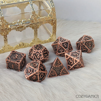 Copper metal gear dice set for DnD TTRPGs, featuring a unique clockwork design, displayed with a decorative treasure chest.