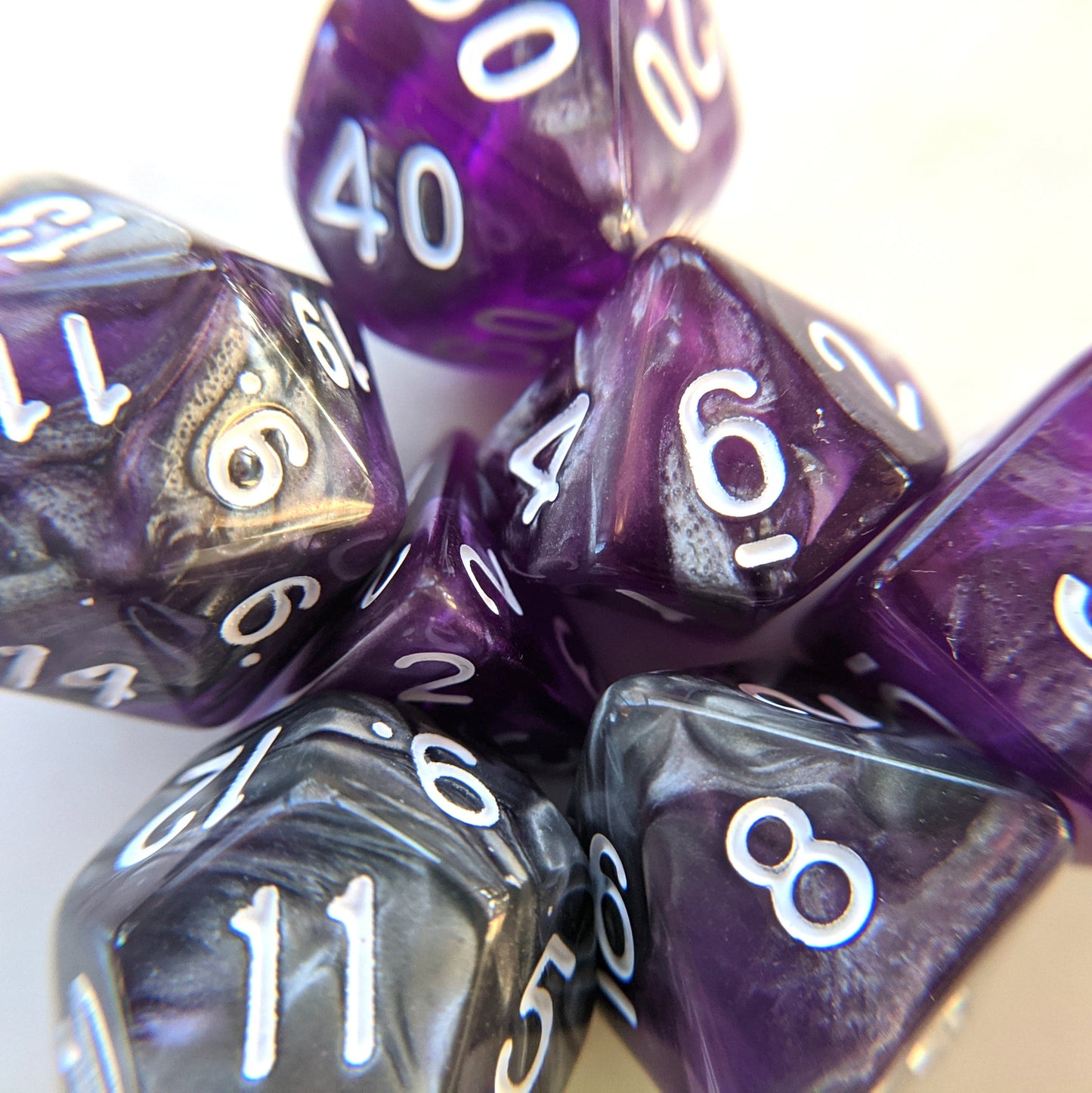 Dark Crystal Dice Set in marbled silver and translucent purple for tabletop RPGs like Dungeons and Dragons, featuring seven polyhedral dice.