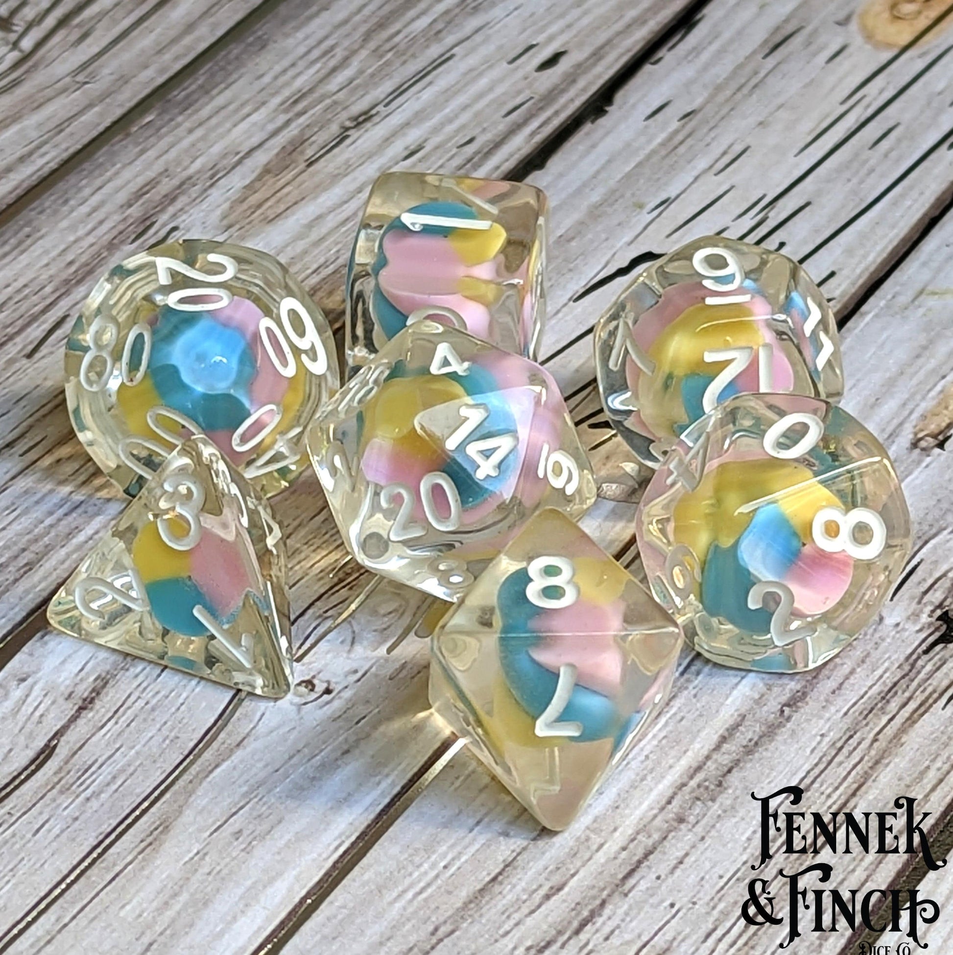 Fae Candy Swirl Dice Set with colorful candy centers for DnD 7 piece polyhedral RPG dice on wooden table.