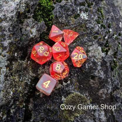 Fire Flick 7 piece red DnD dice set on rock, clear design with red ink, perfect for TTRPG and dice collectors.