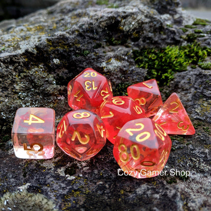 Fire Flick DnD dice set with clear red design, featuring 7 gaming dice on a rustic rock background. Ideal for TTRPG enthusiasts.