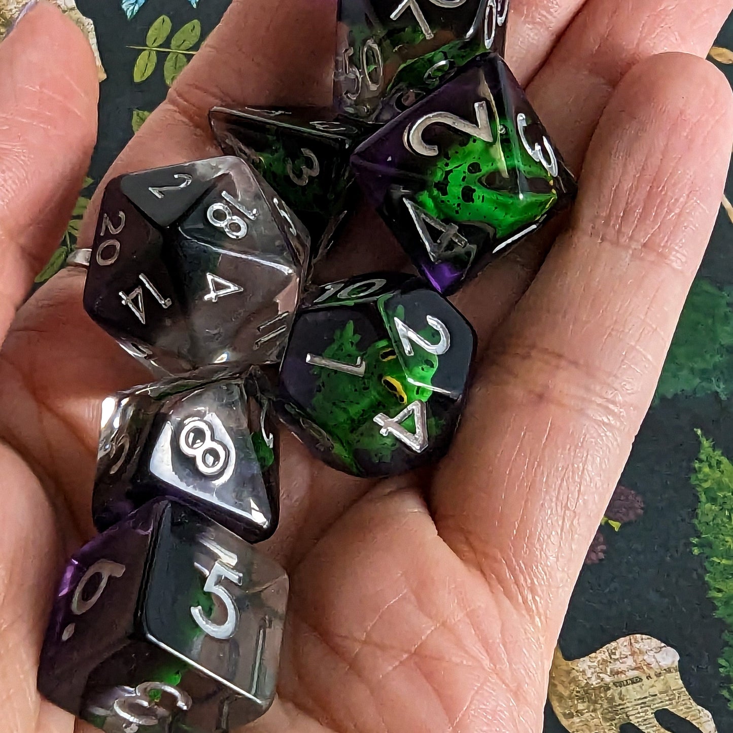 Hand holding Hoppy Hauntings Frog DnD Dice Set with green frogs and clear purple design, perfect for tabletop adventures.