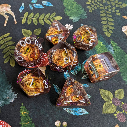 Golden Eye DnD Dice Set with detailed eye design, 7-piece polyhedral set on nature background for tabletop RPGs.