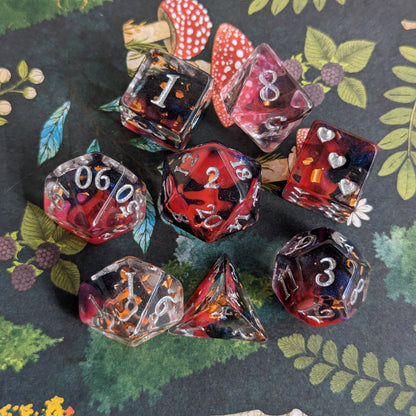 Heart Piercer DND dice set, red with black shadowy ink, shimmering blue highlights, silver fantasy font, forest background.