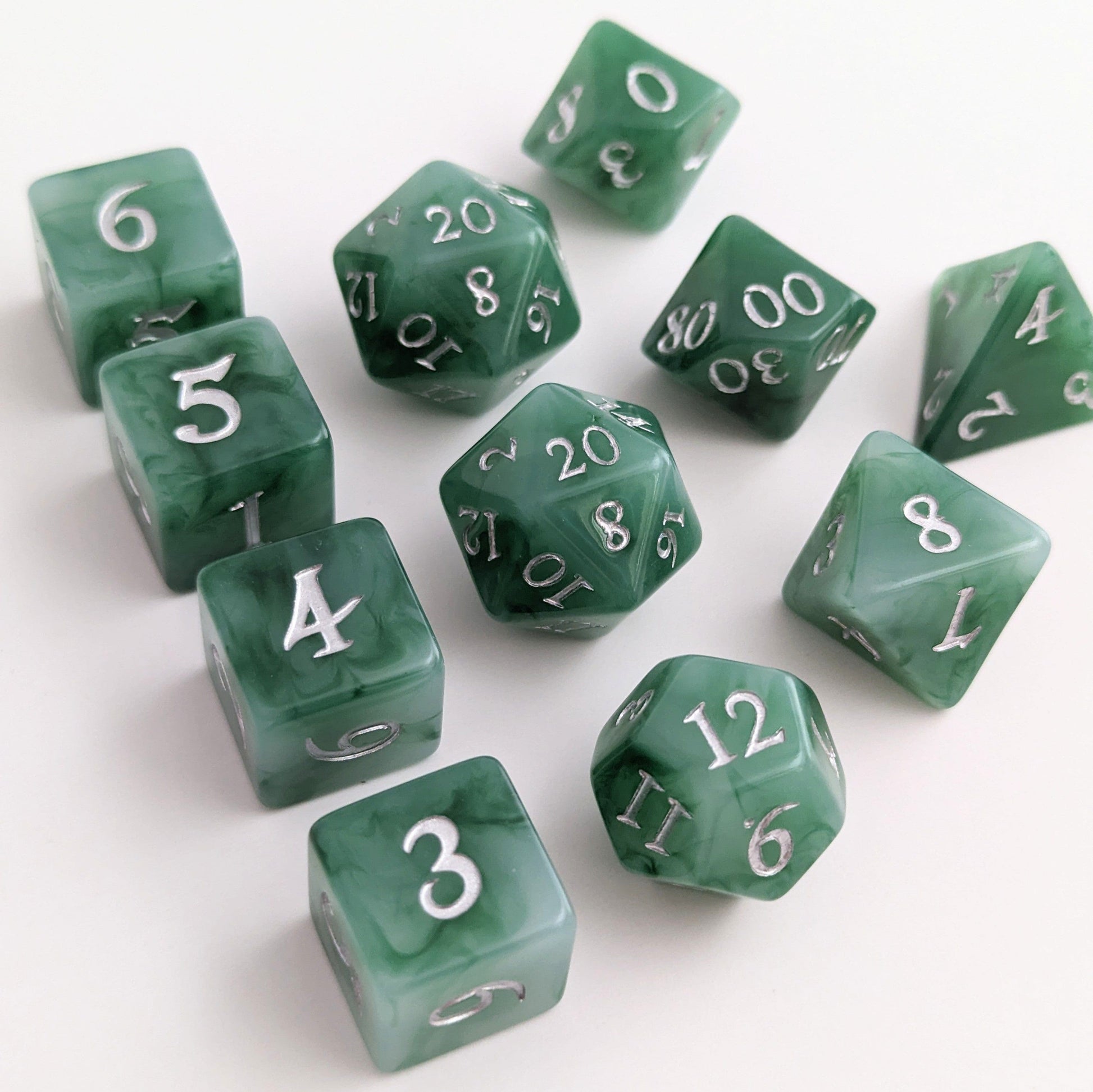 Jade 11-piece DnD dice set with green and white resin, silver fantasy font, ideal for druids or rangers in tabletop RPGs.