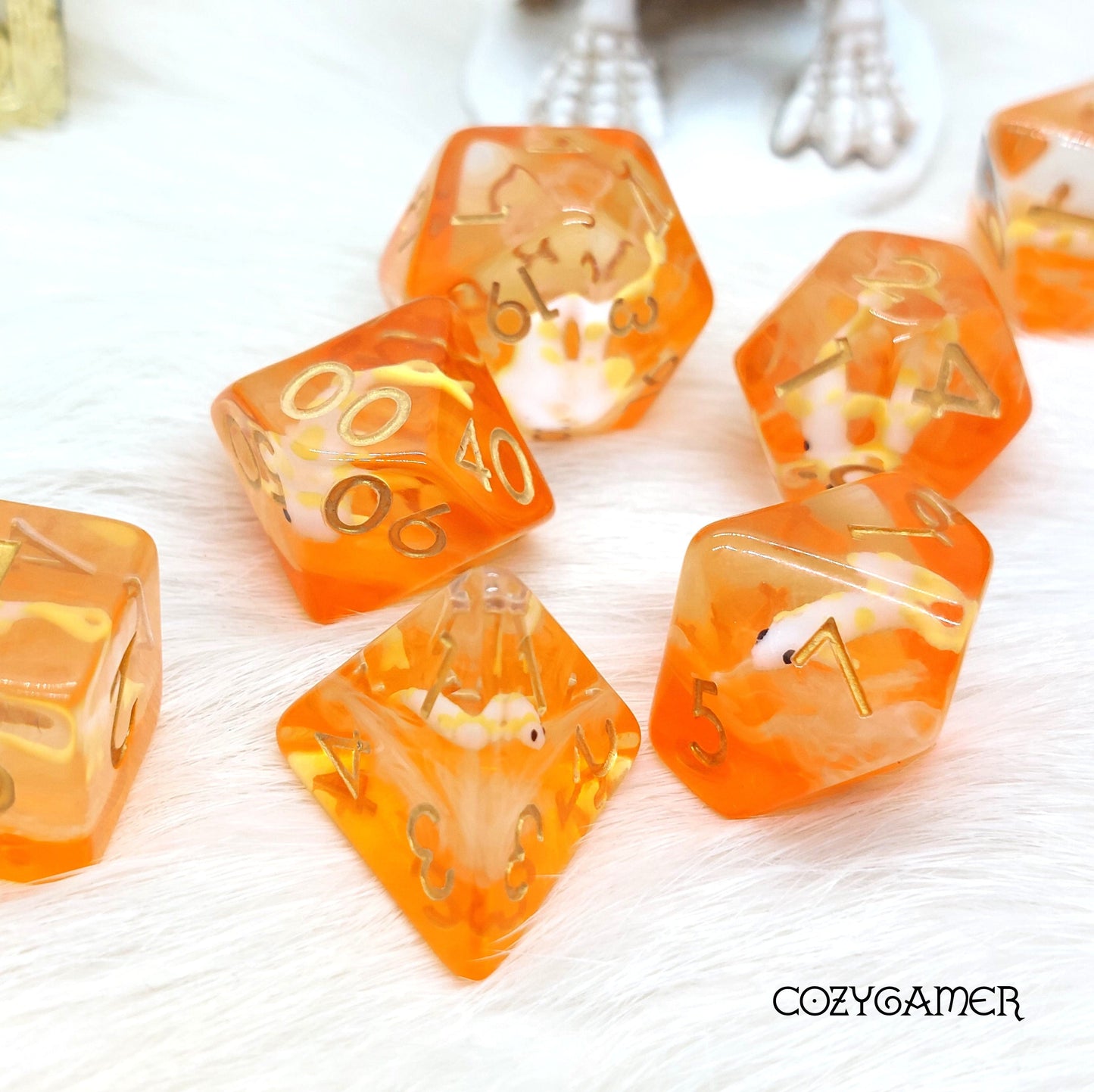 Orange translucent koi fish dice set for tabletop games like Dungeons and Dragons, featuring polyhedral shapes on soft fabric.