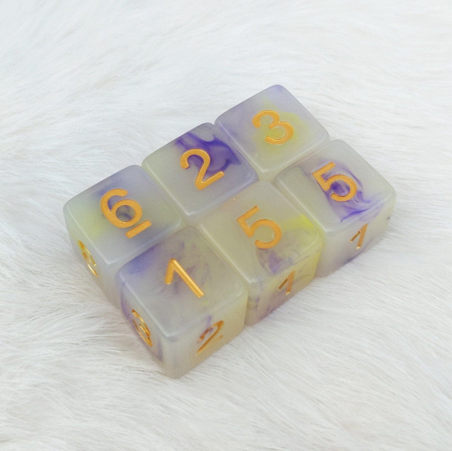 Magic Aura D6 dice set of 6, semi-clear resin with yellow and purple swirls, gold numbers, perfect for DnD and tabletop games.