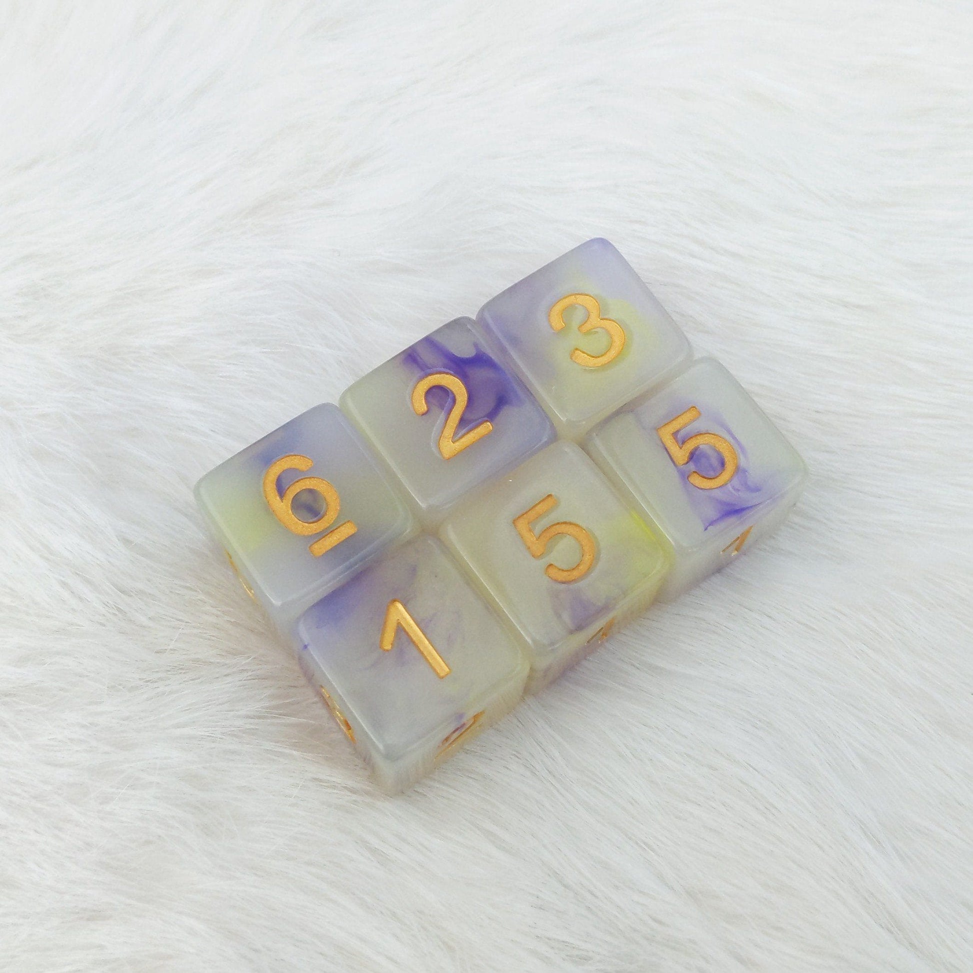 Magic Aura D6 dice set of 6 with semi-clear resin, yellow and purple ink, and gold font on a white surface.