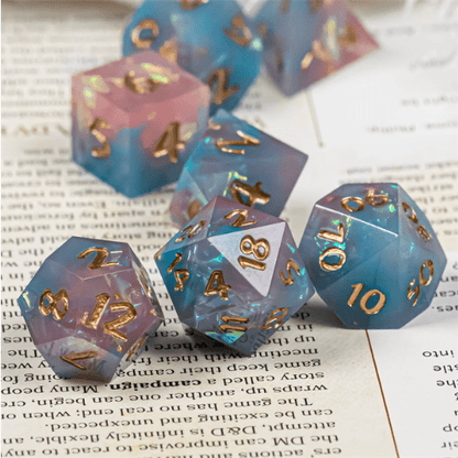 Mauve and blue sharp edge resin dice set with glitter and gold foil, 7 piece polyhedral TTRPG dice for DND gameplay.