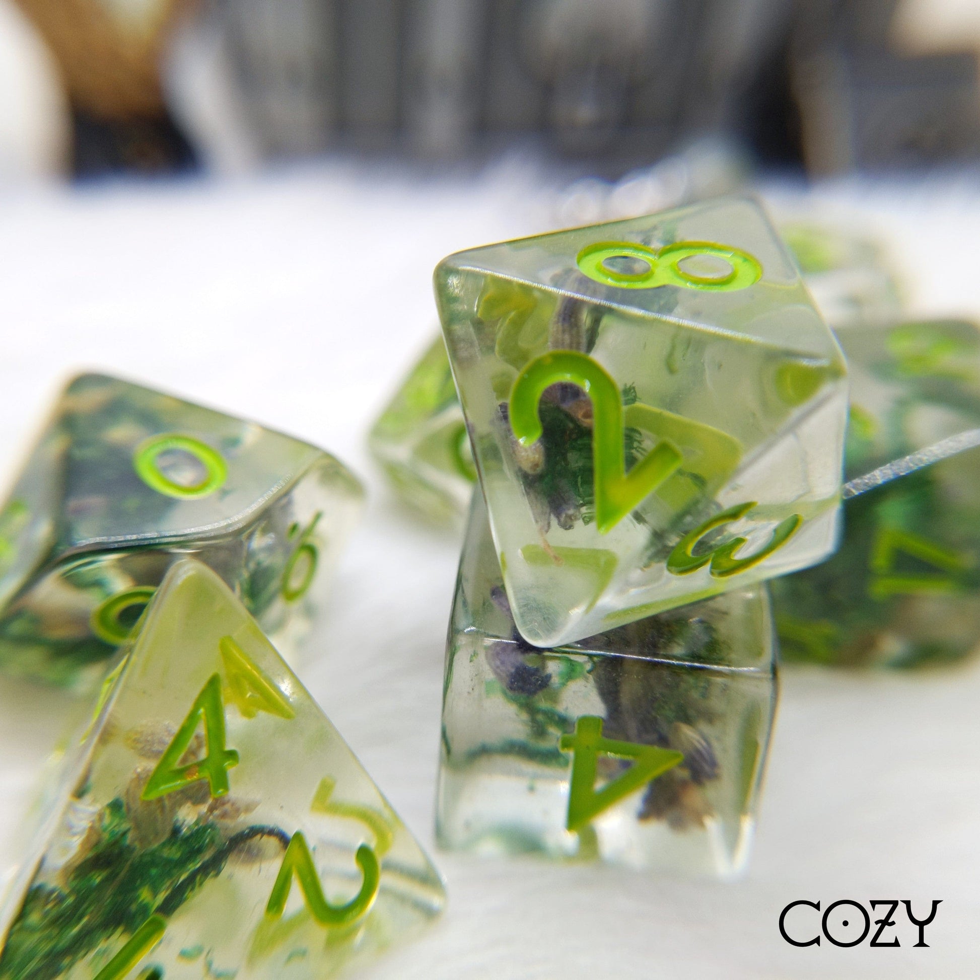 Polyhedral dice set with real moss and lavender encased in clear resin, featuring green numbers, for tabletop RPGs like DnD.