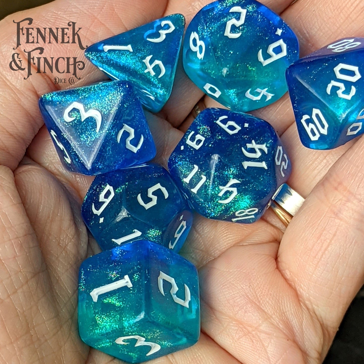 Hand holding Oasis Dice Set with marbled blue shimmering design, perfect for tabletop RPGs like Dungeons and Dragons.