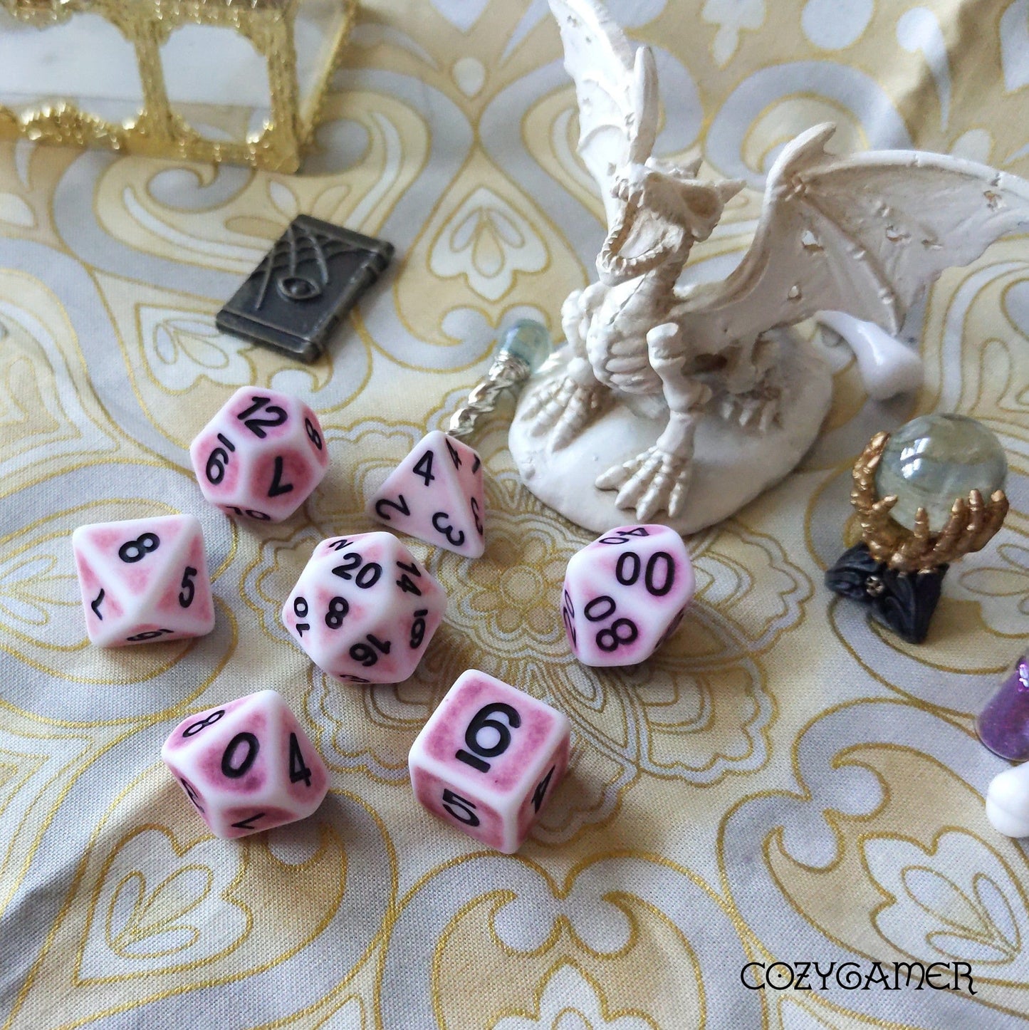 Pink Ancient Dice Set with dragon figurine, featuring 7 polyhedral dice in pink resin with black font for tabletop RPGs.