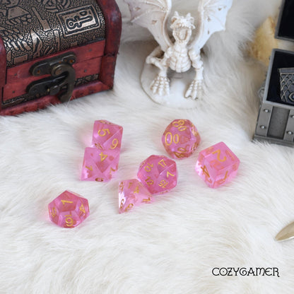 Pink crystal dice set for Dungeons and Dragons on white fur with fantasy accessories.