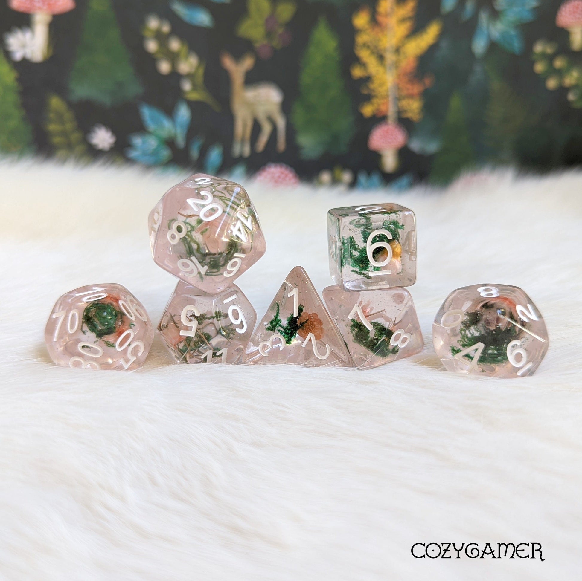 Pink flower and moss dice set with real dried plants in clear resin, 7 polyhedral pieces for DnD, on a soft background.