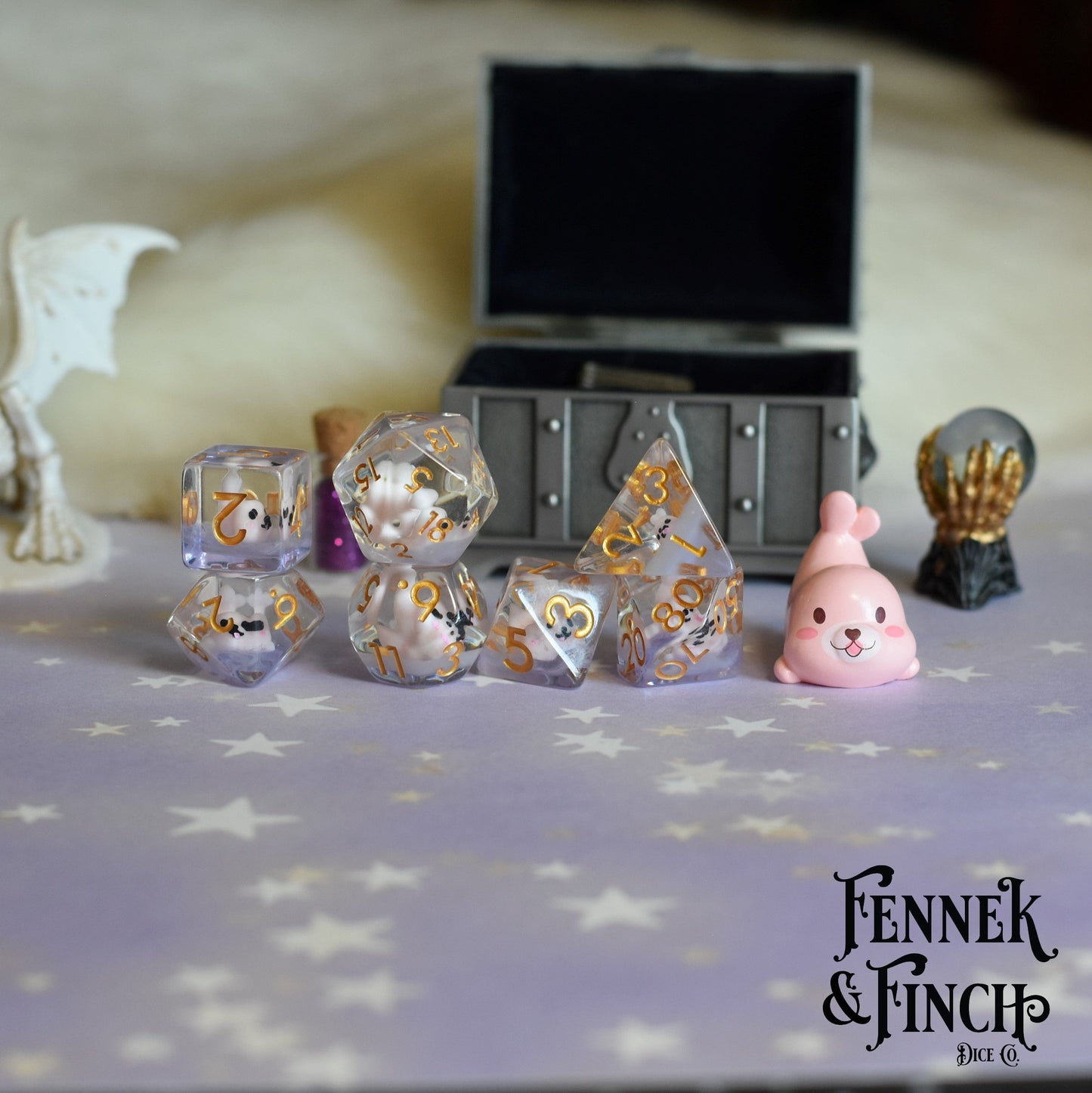 Pink Seal Dice Set with purple resin and cute animal figures for tabletop games, shown with a treasure chest in the background.