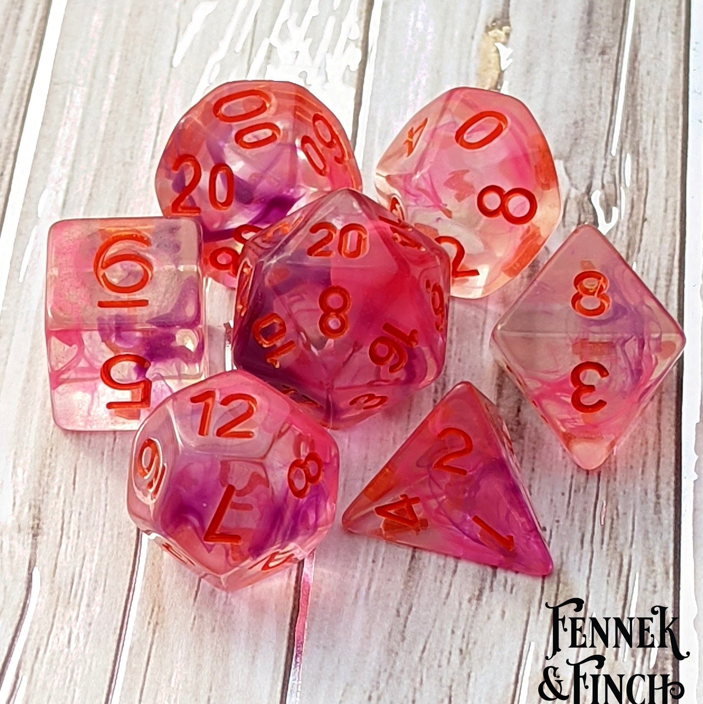 Translucent Poisonous Flower DnD dice set with pink and purple swirls and red numbers, designed by Therin of Cozy Gamer.