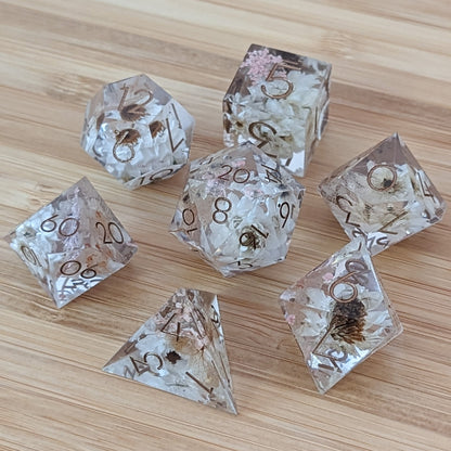 Prairie Flowers Sharp Edge DnD Dice Set with daisies, Queen Anne's Lace, and Hydrangea leaves in clear resin on wooden surface.