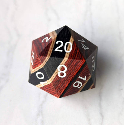 Red, black, and light wood striped large wooden D20 dice on marble surface, ideal for collections and gaming enthusiasts.