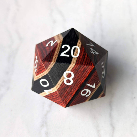 Red, black, and light wood striped large wooden D20 dice on marble surface, ideal for collections and gaming enthusiasts.