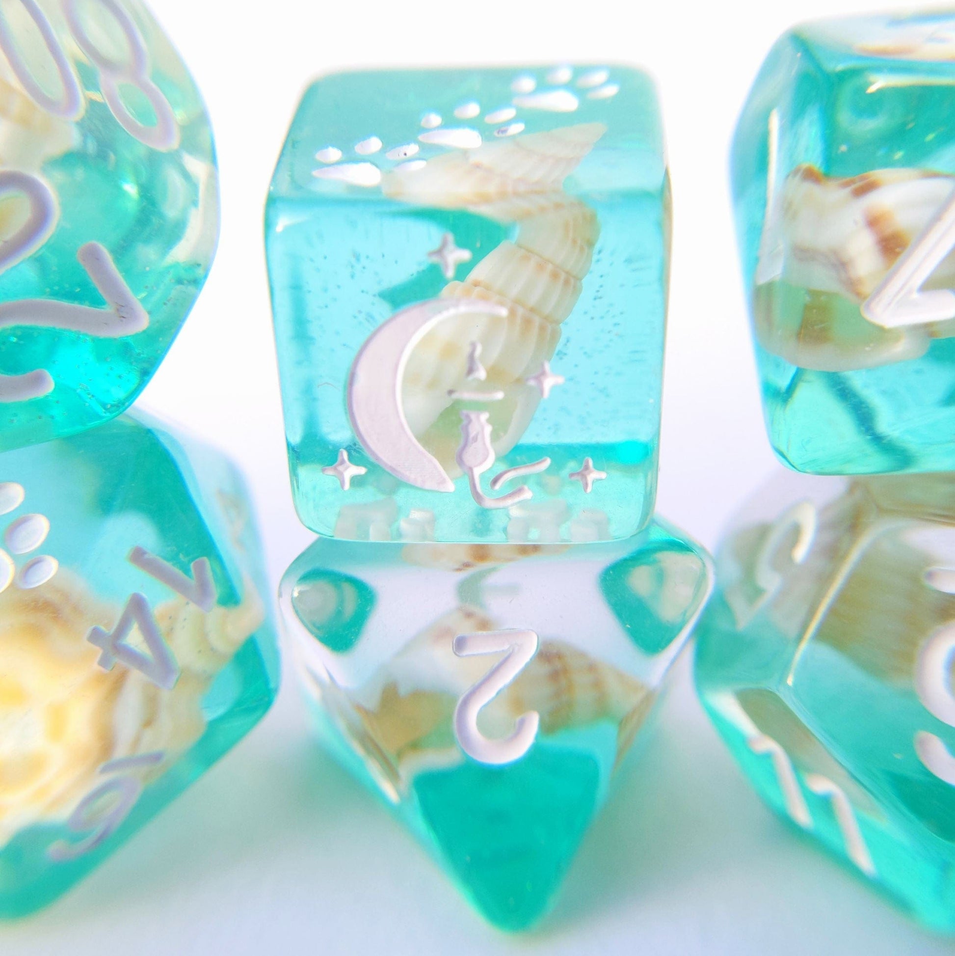 Sea Shell DnD Dice Set with teal resin and white font, featuring cat wizard on crescent, star, and paw designs for tabletop RPGs.