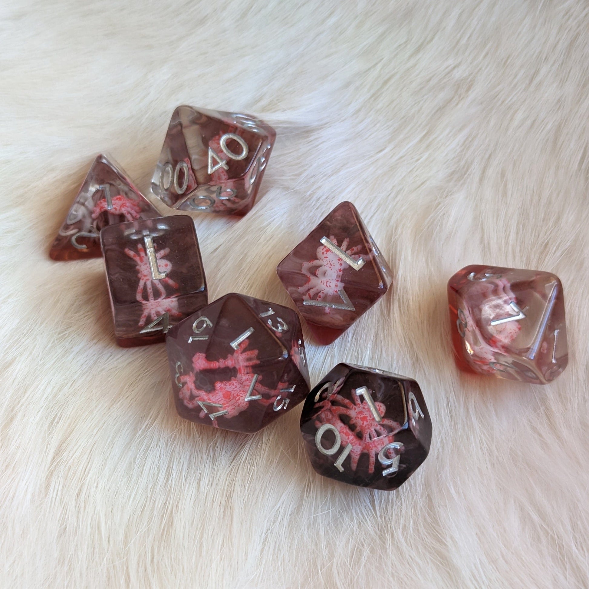 Spider-themed 7-piece resin DND dice set with intricate inclusions displayed on a soft fur background.