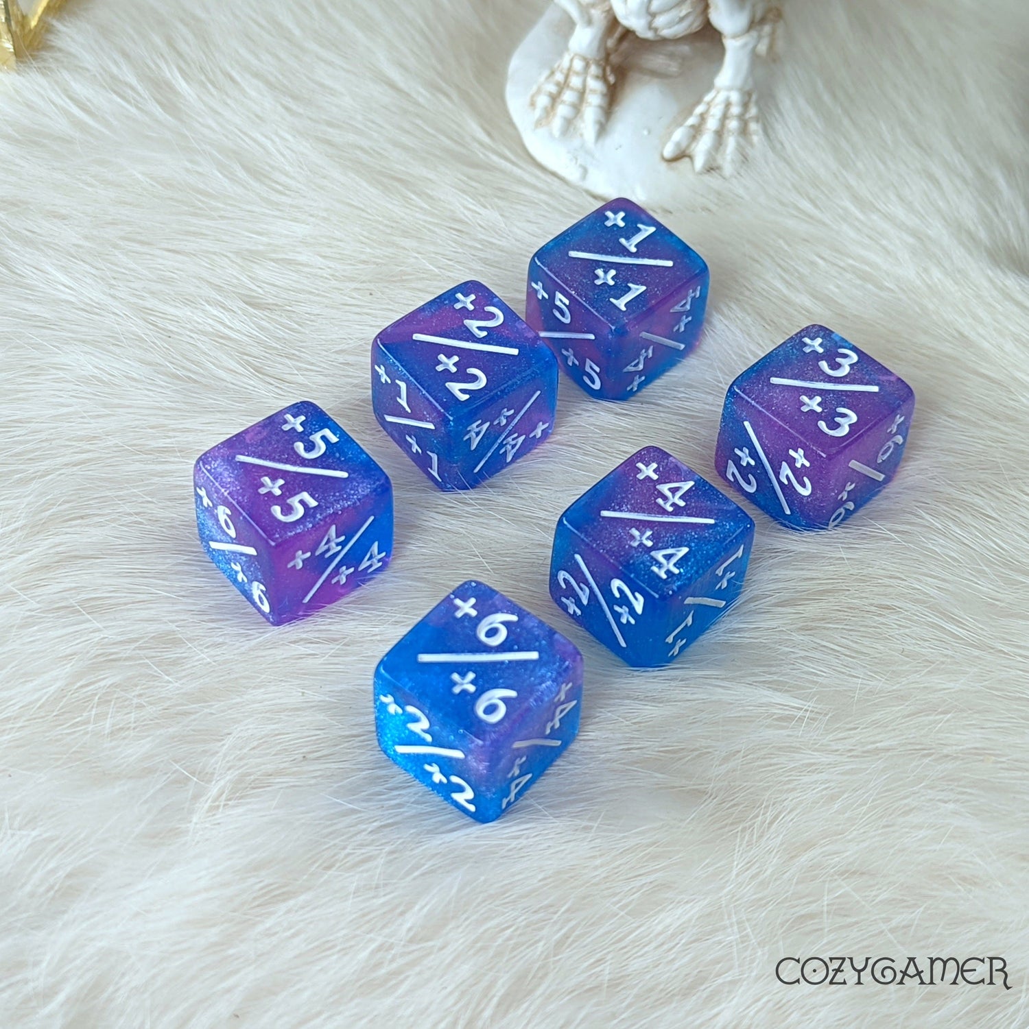 Starry Sky D6 counter dice set, 6 blue and purple glittering acrylic dice with positive counters, on a soft white surface.