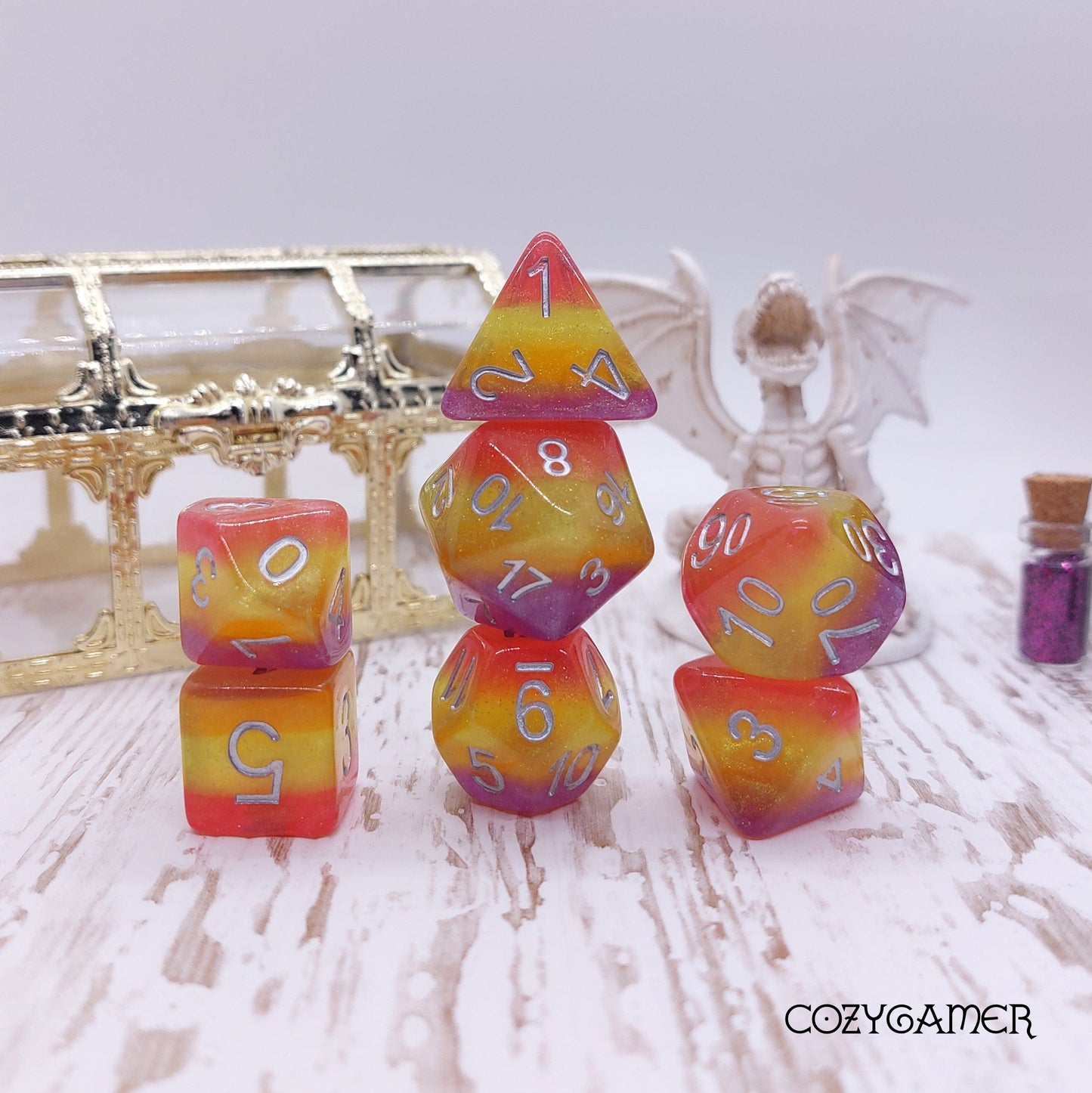 Summer Sunset Dice Set with glitter layers, 7-piece polyhedral dice for TTRPGs like Dungeons and Dragons, on display with decor.