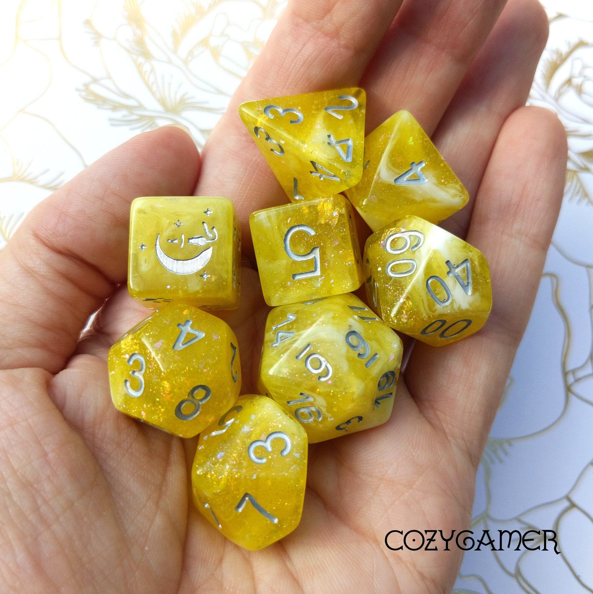 Sunlight 8 Piece Dice Set in clear yellow resin with glitter, featuring a cat wizard design, held in a hand. Exclusive Fennek & Finch.